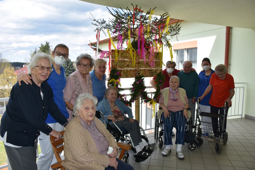 Personen stehen bei Maibaum