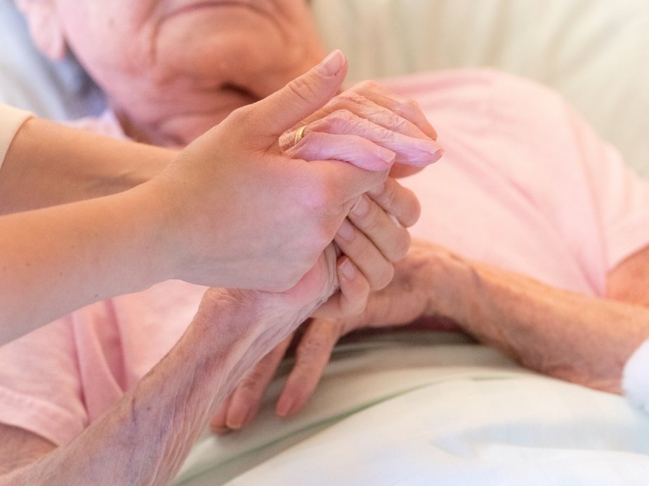 Eine Betreuerin hält die Hand einer Bewohnerin.